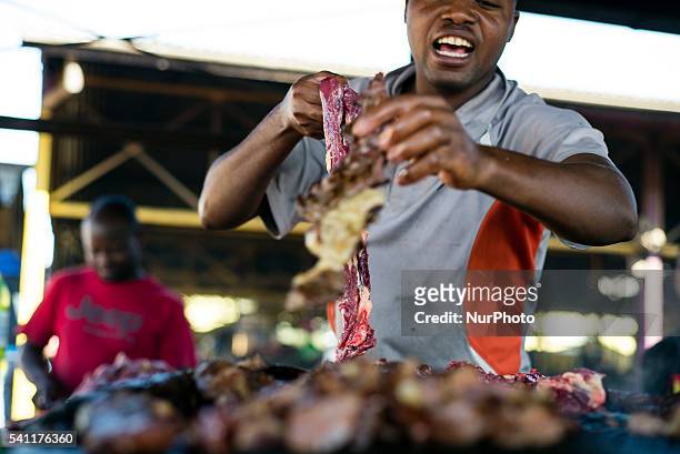 Kapana man calls for customers at Katutura open market, Windhoek, Namibia. Kapana is a grilled beef meet. Seller cuts it into pieces and prepares it...