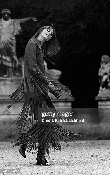 Actress Jane Birkin wearing laced suede tunic with fringe with matching knee-long pants by Ossie Clark and boots by Francois Villon; Birkin whirling...