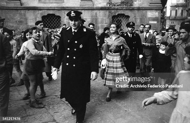Actress Ingeborg Schoner is escorted through the town by Italian police. A crowd of fans follow her through the streets.