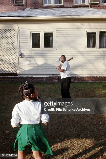 Martin Luther King Jr. Plays baseball with his daughter Yolanda in their backyard.