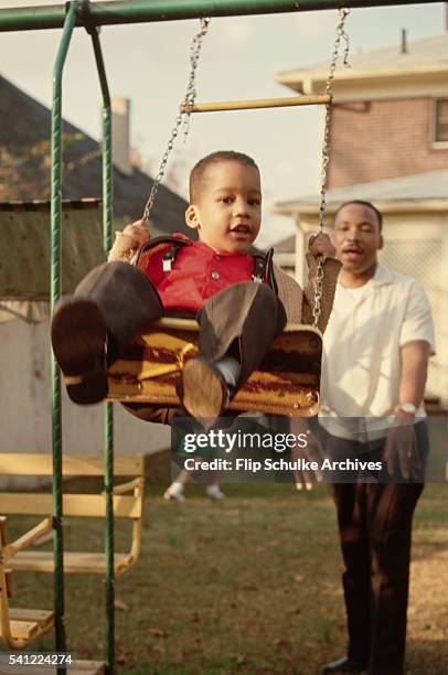 Martin Luther King Jr. Pushes his young son Dexter on a swing set in their backyard.