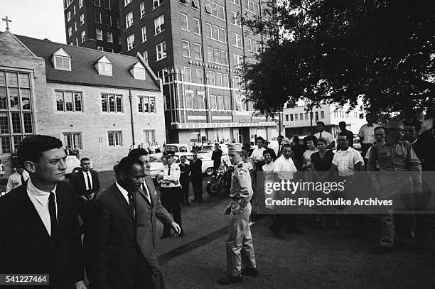 James Meredith, U.S. Attorney John Doar, and U.S. Marshal James J.P. McShane stroll past police and onlookers during their fight against the state of...