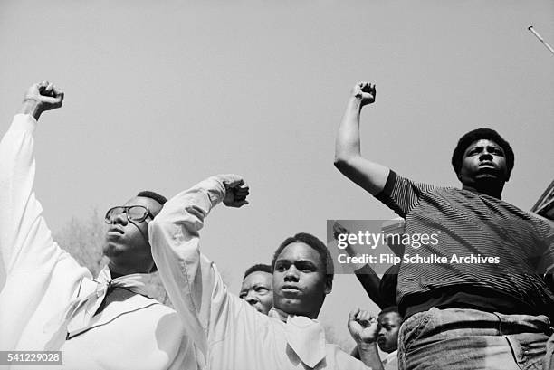 Several young men raise their fists in the black power salute at a civil rights rally, circa 1970.