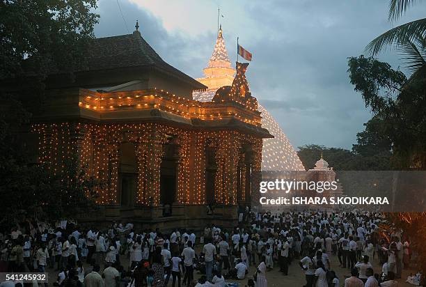 Sri Lankan Buddhist devotees gather around an illuminated temple during Poya, a full moon religion festival, at the Kelaniya Temple in Kelaniya on...