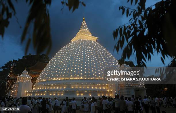 Sri Lankan Buddhist devotees gather around an illuminated temple during Poya, a full moon religion festival, at the Kelaniya Temple in Kelaniya on...