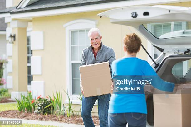senior couple moving boxes in trunk of car - omstrukturering bildbanksfoton och bilder