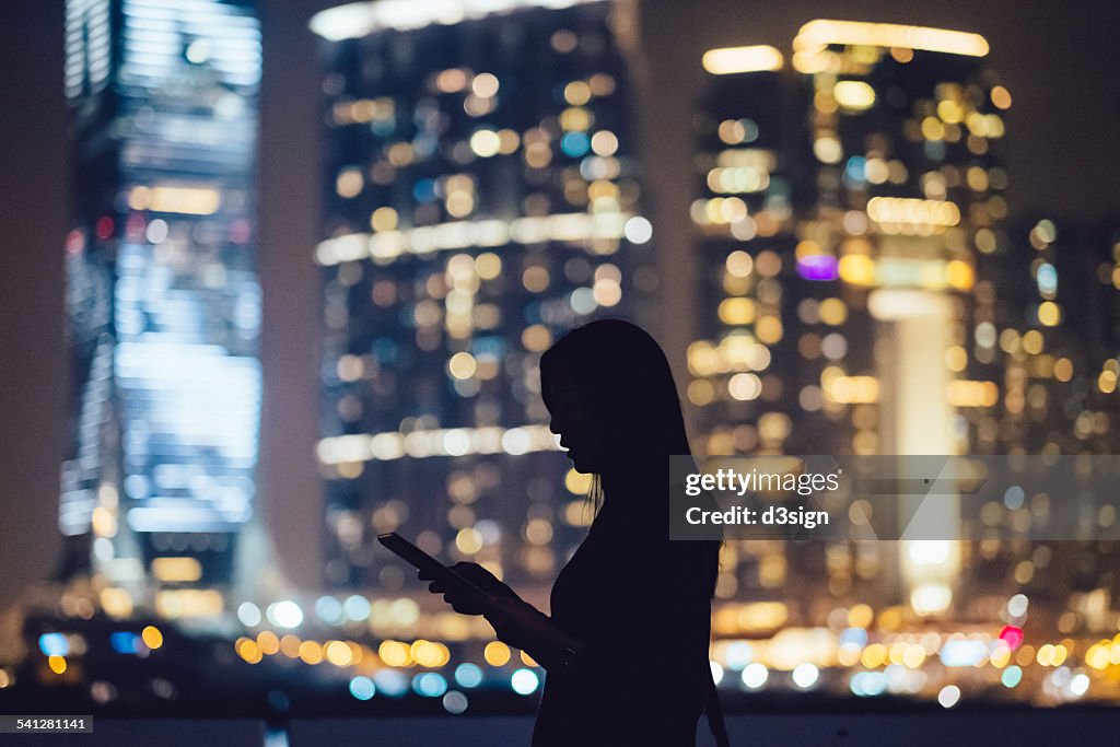 Silhouette of woman with digital tablet in city