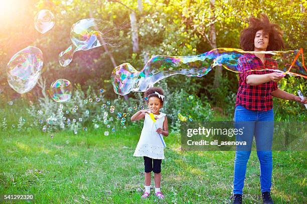 happy mother and her daughter playing soap bubbles in park. - mystical baby girls stock pictures, royalty-free photos & images