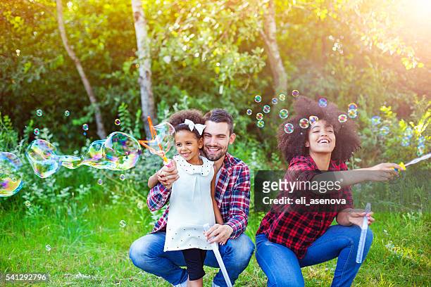 happy family playing soap bubbles in park. - mystical baby girls stock pictures, royalty-free photos & images