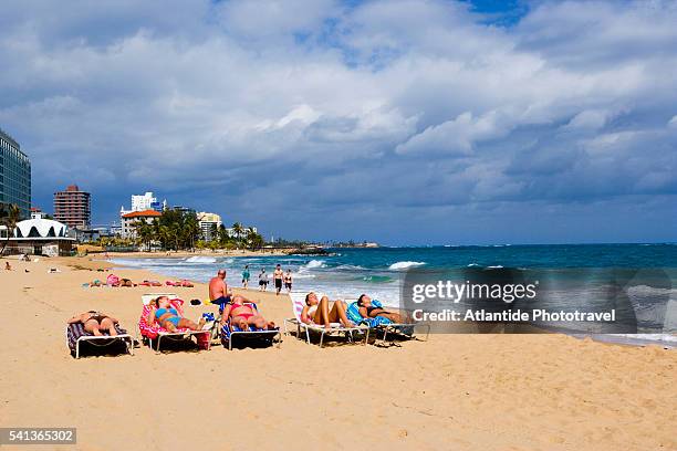 sunbathing on condado beach in san juan - condado beach stock pictures, royalty-free photos & images