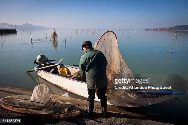 lago (lake) trasimeno, fisherman at work near san feliciano village - lac trasimeno photos et images de collection