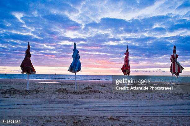 closed beach umbrellas at sunset - trouville sur mer stock-fotos und bilder