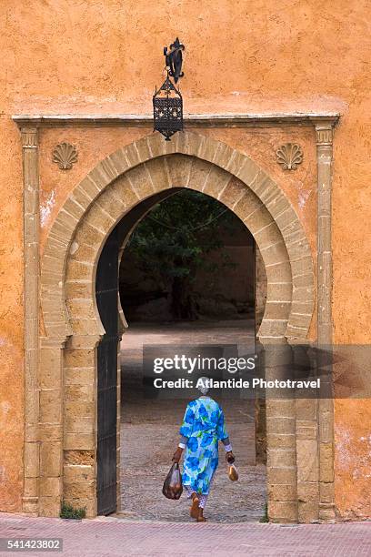 woman walking through entrance to the kasbah des oudaias - casbah stock pictures, royalty-free photos & images