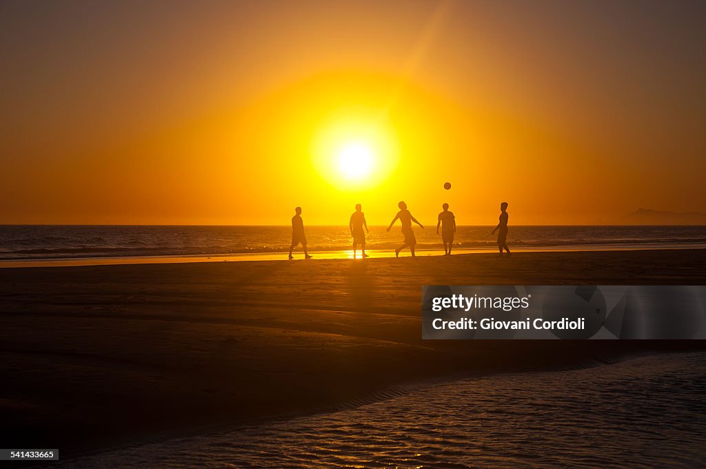 Friends playing soccer on the beach