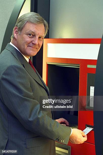 Manager, DVorstand der Hamburger Sparkasse steckt eine EC-Karte in einen Geldautomaten. - ohne Jahr.