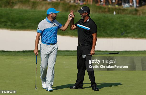 Sergio Garcia of Spain is greeted by Scott Piercy of the United States after Garcia holed a bunker shot for birdie on the eighth hole during the...