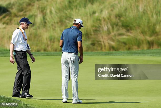 Dustin Johnson of the United States chats with a rules official on the fifth green during the final round of the U.S. Open at Oakmont Country Club on...