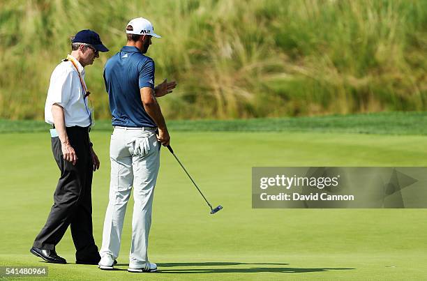 Dustin Johnson of the United States chats with a rules official on the fifth green during the final round of the U.S. Open at Oakmont Country Club on...