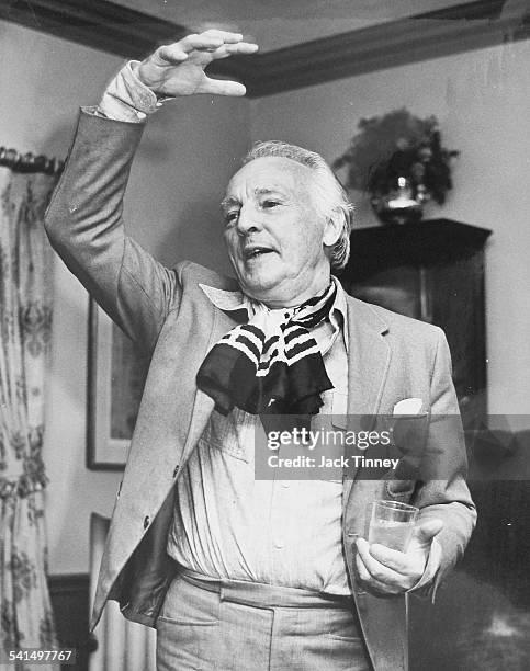 Portrait of Russian-born American choreographer and dancer George Balanchine as he gestures theatrically with one hand and holds a brink in the...