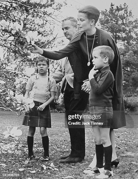 Princess Grace of Monaco examines a flower during a visit to her childhood home, surrounded by her family, from left, daughter Princess Caroline ,...