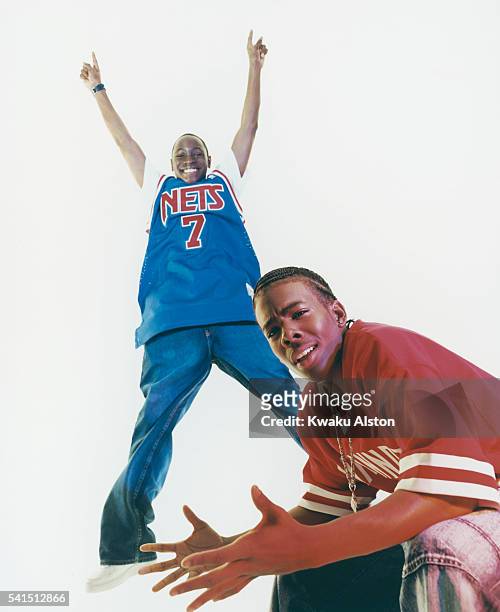 Corey holds up both arms as he wears a New Jersey Nets jersey, while Mario sits nearby in a Cincinnati Reds jersey.