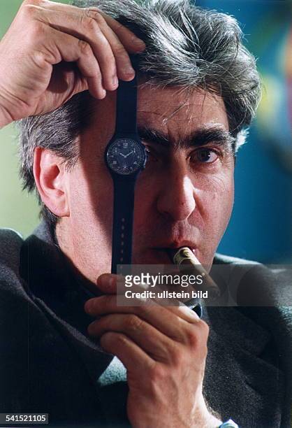 Unternehmer; SchweizVorstandsvorsitzender der Uhrenfirma Swatch AG Porträt mit Zigarre und einer Armbanduhr vor dem Gesicht