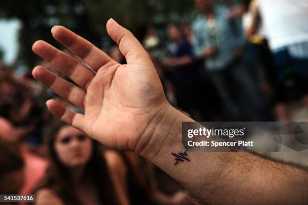 Man displays a "Pulse" tatto in solidarity with the victims during a memorial service on June 19, 2016 in Orlando, Florida. Thousands of people are...