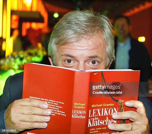 Journalist; DKlatsch-Reporter schaut hinter seinem Buch: "Lexikon des Klatsches " hervor