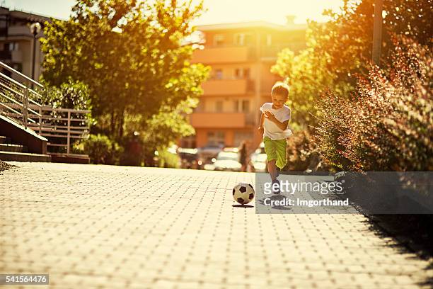 little boy playing soccer on the street - hot boy pics stockfoto's en -beelden