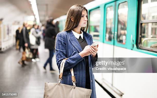 young woman checking timetables on smartphone before getting onto train - paris metro stock pictures, royalty-free photos & images