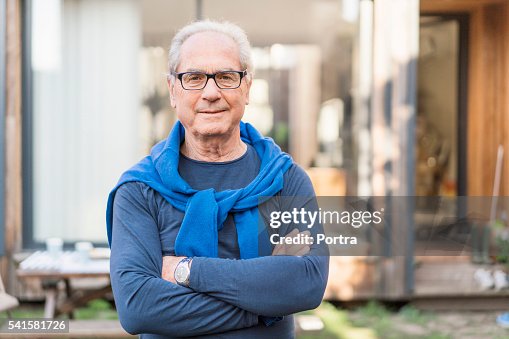 Confident senior man with arms crossed in backyard Confident senior man with arms crossed in backyard