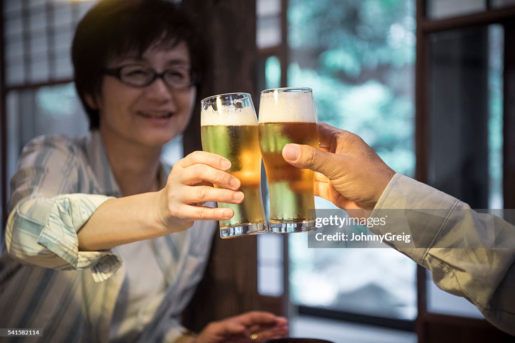 Mature Japanese woman toasting beer with man