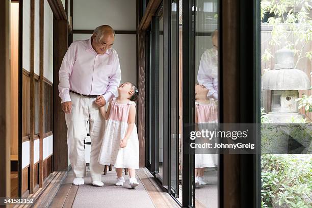 young japanese girl looking up at grandfather holding hands - japanese respect stock pictures, royalty-free photos & images