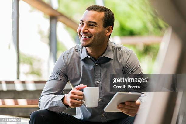 businessman with mug and digital tablet on steps - 30 39 jaar stockfoto's en -beelden