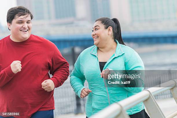 overweight man and woman jogging in the city - zware lichaamsbouw stockfoto's en -beelden