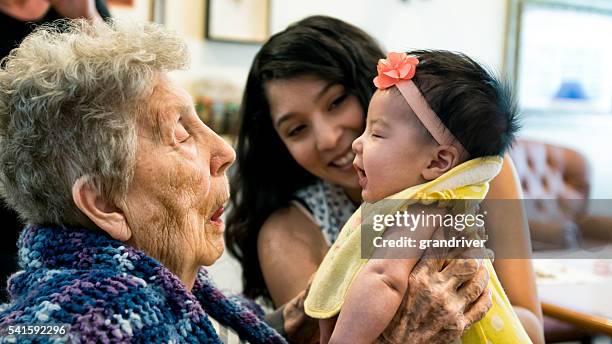 ältere frau hält kleine enkelin als mutter lächelnd sieht aus auf - black mother holding newborn stock-fotos und bilder