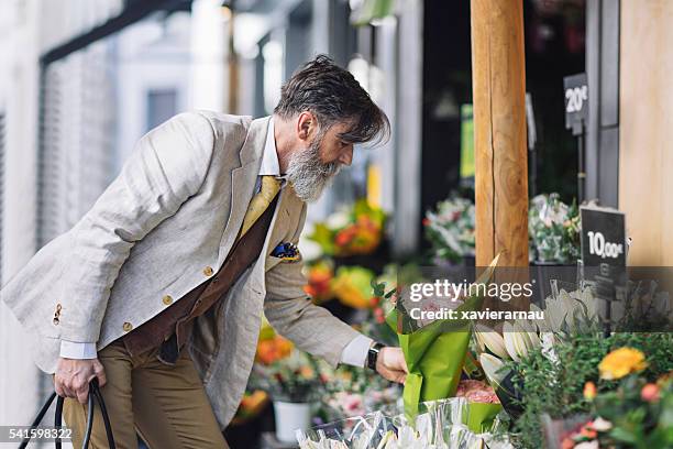 mature man buying flowers in flower shop - man picking flowers stock pictures, royalty-free photos & images