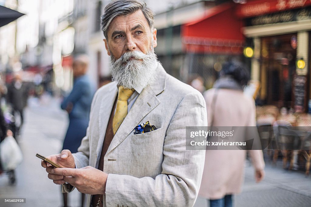 Bearded mature man texting at the street