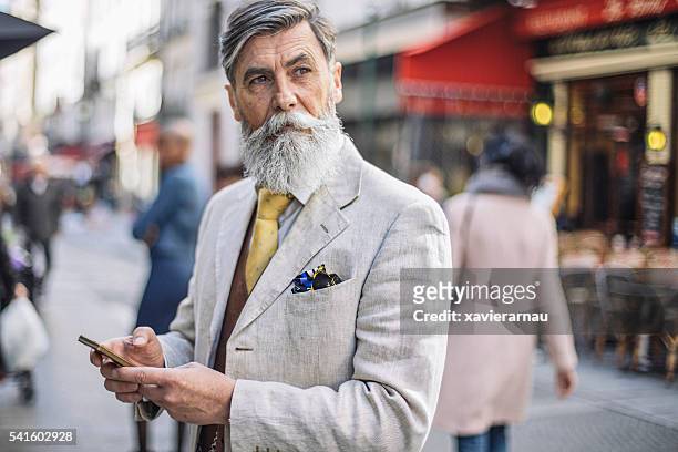 bearded mature man texting at the street - cool attitude stock pictures, royalty-free photos & images
