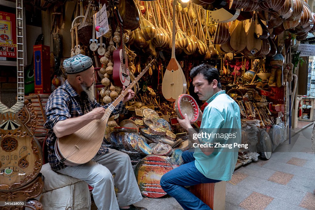 Two Uygur men plays traditional Dutar and hand drum beside a...