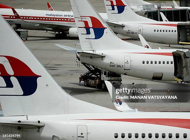 Malaysia Airlines ground staff walk past Malaysia Airlines aircraft parked on the tarmac at the Kuala Lumpur International Airport in Sepang on June...