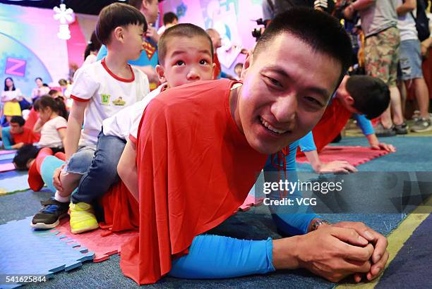 Father dressed as Superman carrying his child on the back competes push-ups to celebrate Father's Day on June 19, 2016 in Hangzhou, Zhejiang Province...