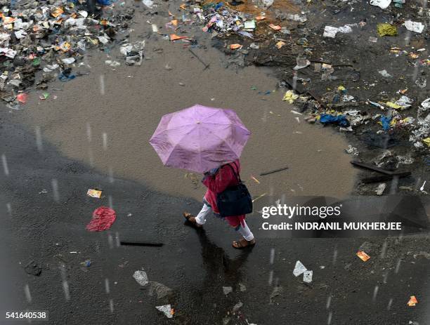 An Indian officegoer walks during a downpour in Mumbai on June 20, 2016. - Annual monsoon rains have progressed to parts of western and central...