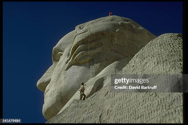 Workers scale the faces of Mount Rushmore while doing annual maintenance work on the four US presidents. George Washington is visible here. The...