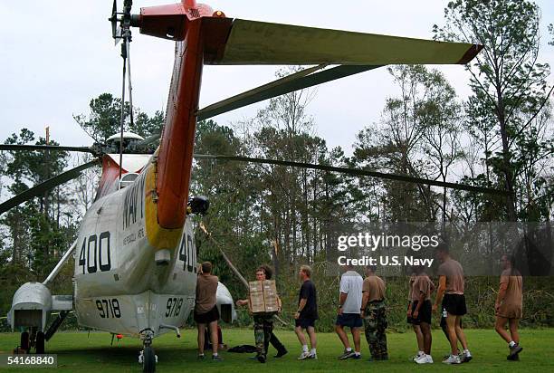 Navy Sailors and civilian personnel unload food and water from a UH-3H Sea King helicopter, transported from Naval Air Station Pensacola, Florida to...