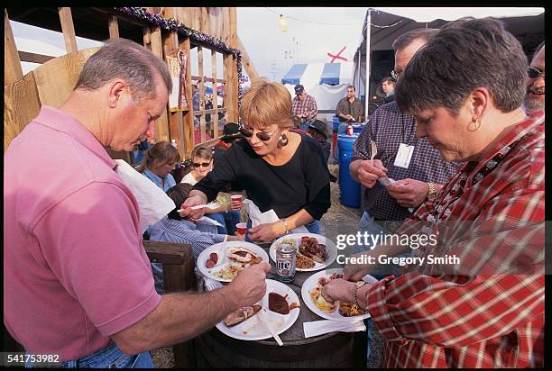 People stand around a table, sampling food at the annual World's Championship Bar-B-Que Contest at the Houston Livestock Show and Rodeo.