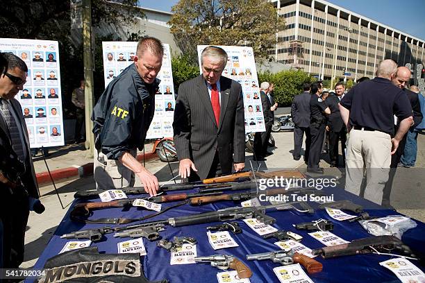 Acting Director Michael Sullivan is shown seized weapons by an ATF officer during a press conference in Los Angeles. 61 members of the Mongols...