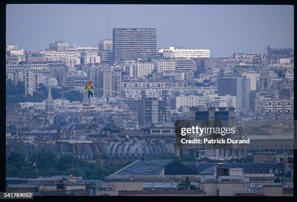 Philippe Petit walks a high wire against the urban backdrop of Paris erected between Trocadero and the Eiffel Tower. He is carrying the Declaration...