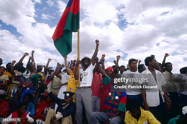 Group of Namibians brandish a flag and raise their fists at a political meeting of the South-West Africa People's Organization before the national...