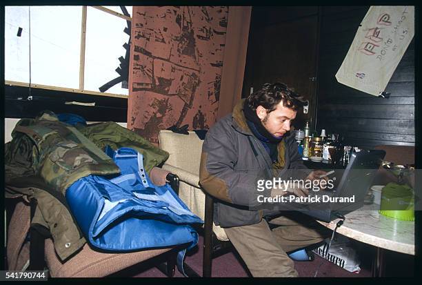 Liberation journalist Didier Francois preparing an article on a laptop at the AFP desk at the bombed Holiday Inn in Sarajevo.
